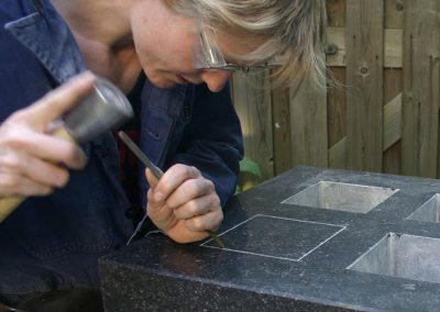 grafkunstenaar aan het hakken in een van de grafstenen